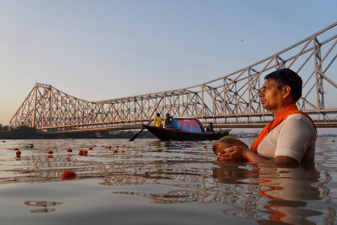 a man sitting in the water next to a bridge