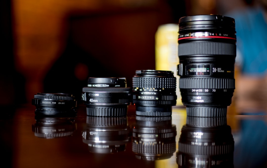 selective focus photography of four black DSLR camera lens on brown wooden surface