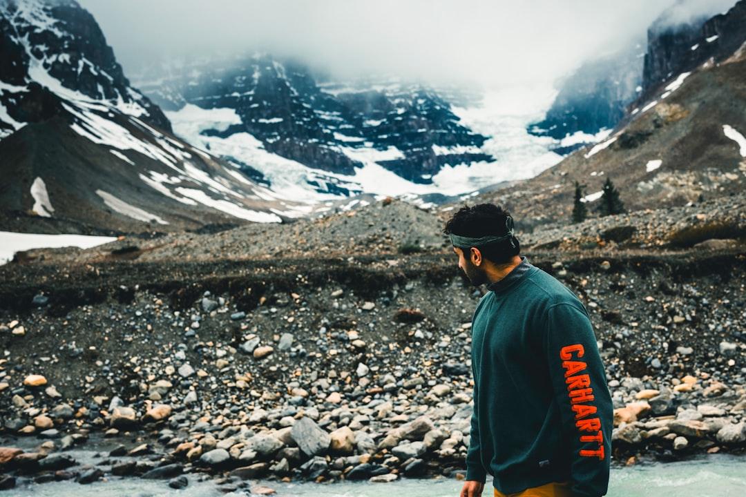 a man standing in a river with mountains in the background